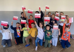 Uczniowie klasy 2b prezentują wykonane flagi Polski.